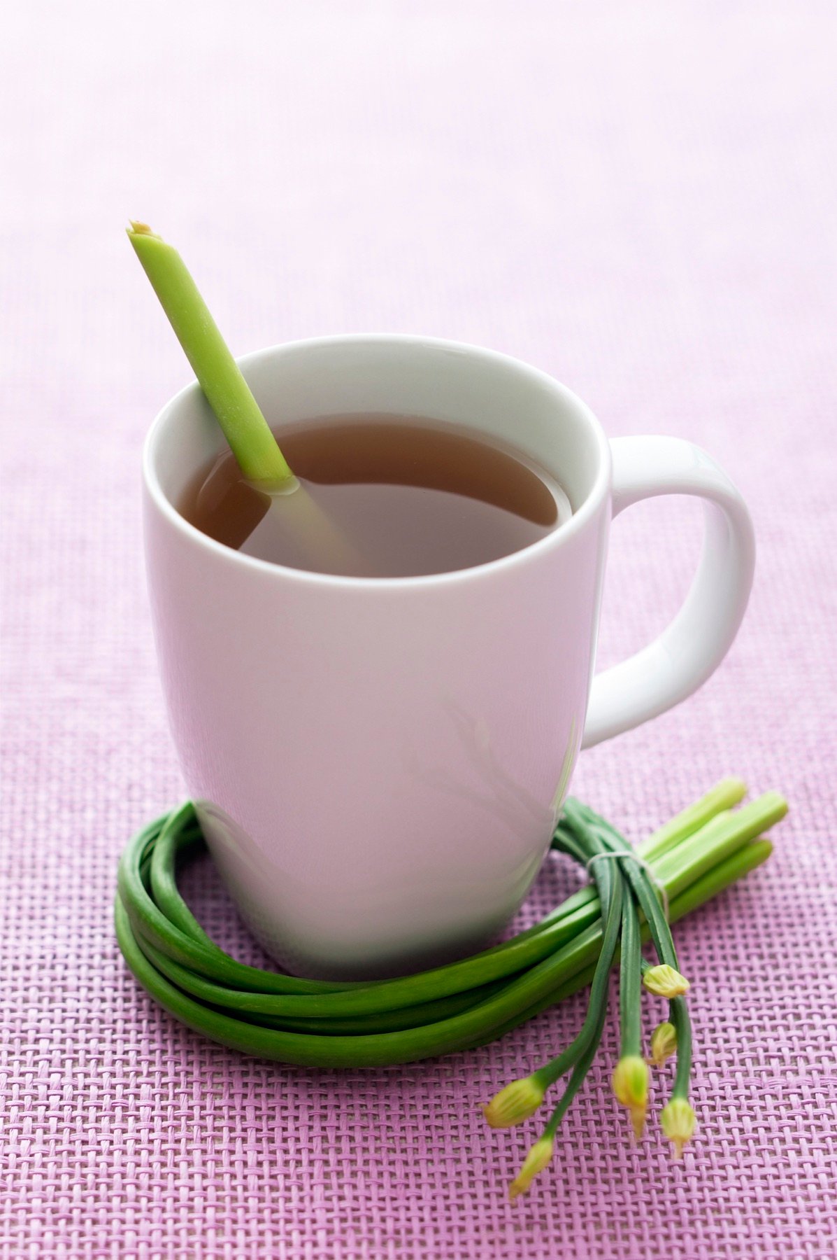 Tea in a white cup with fresh green leaves