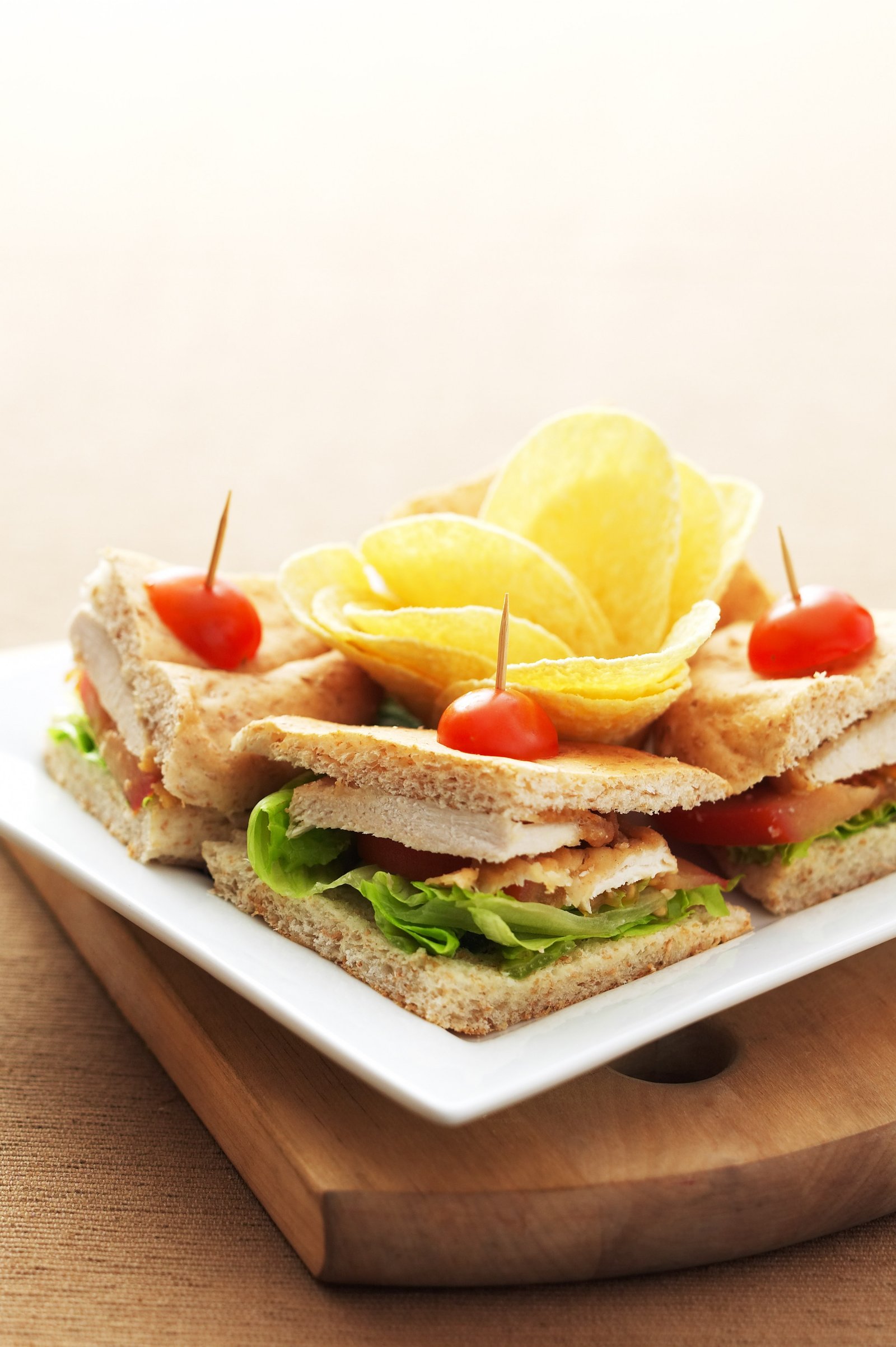 A stacked sandwich with crisps and fresh garnish