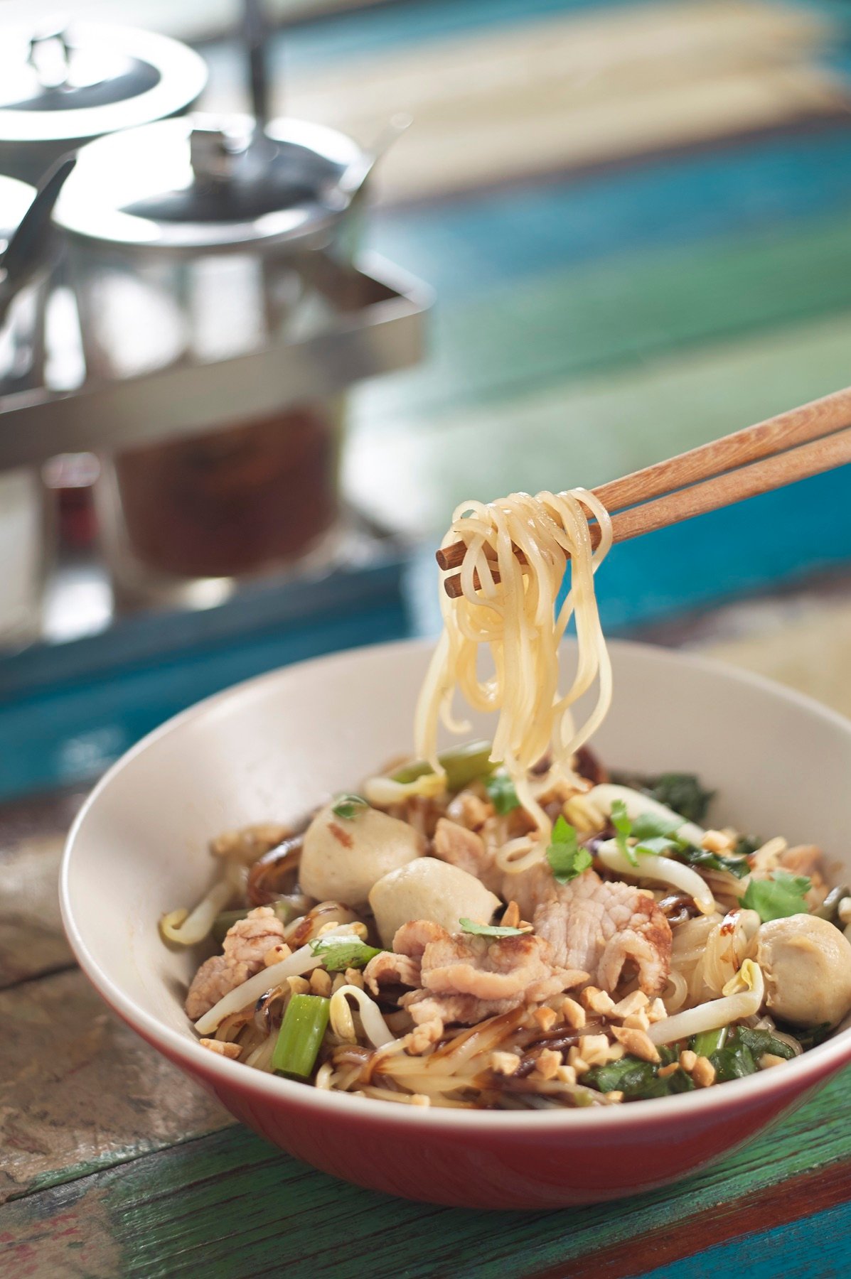 A bowl of noodles with tender meat and greens