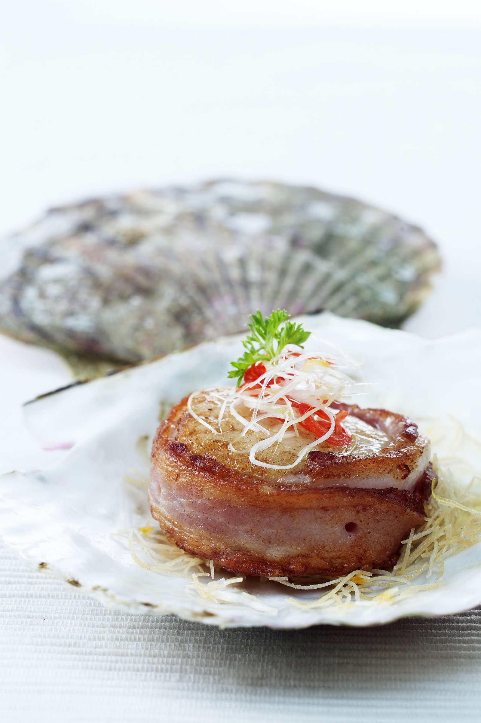 A seafood dish plated beside a fresh oyster